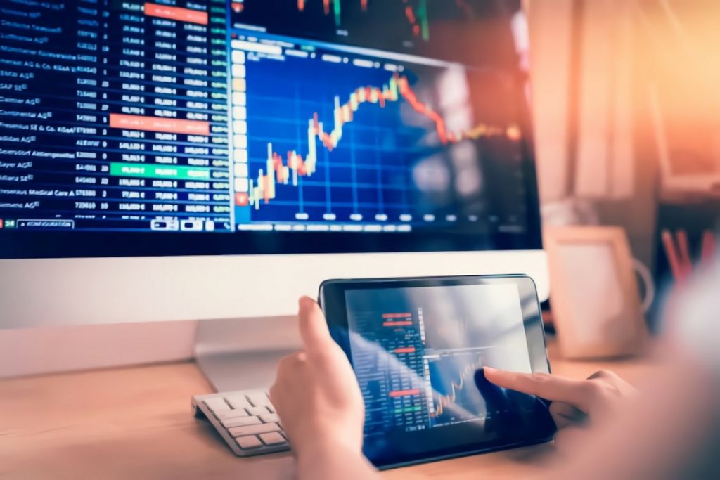 Computer and tablet screens with investment graphs