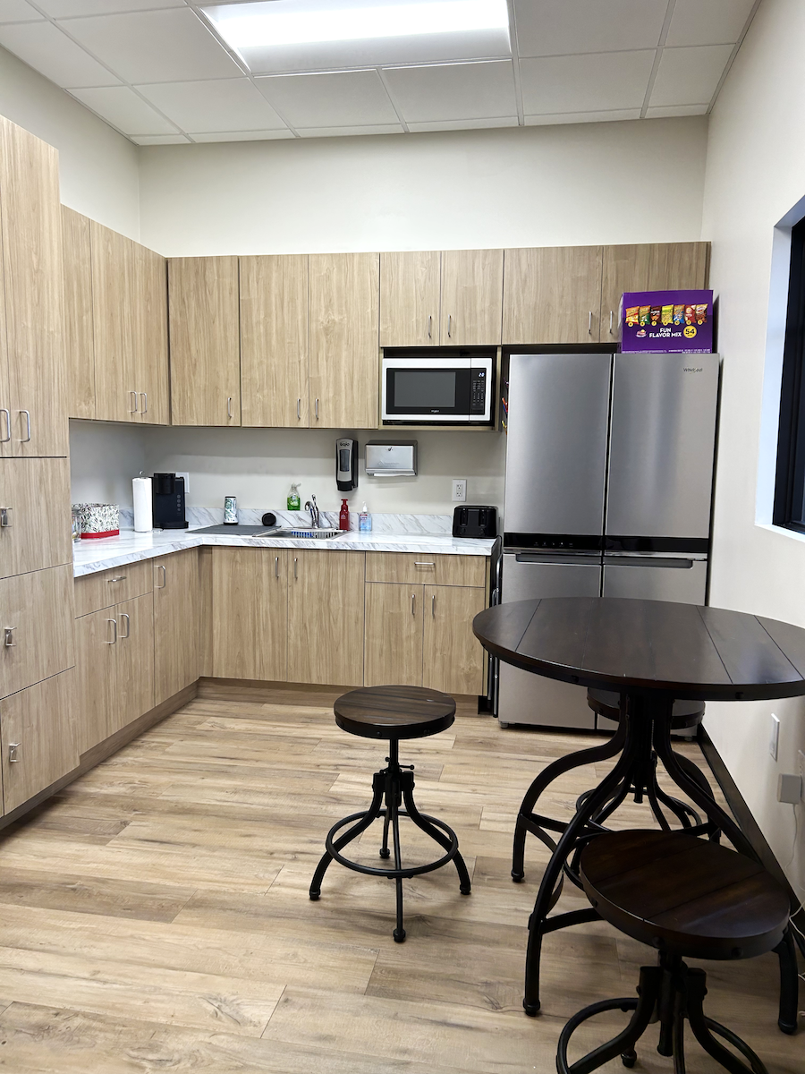 Break room with fridge, cupboards and table