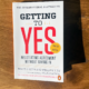 White book titled "Getting to Yes" on wood table