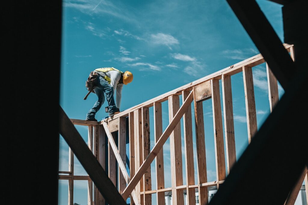 Man in hard hat stands on wall beams