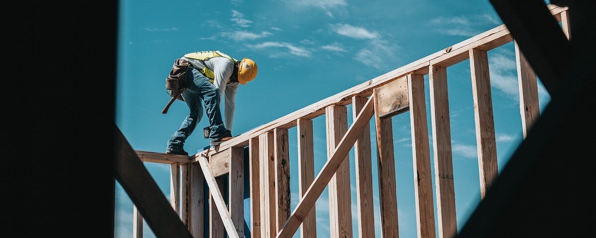 Man in hard hat stands on wall beams