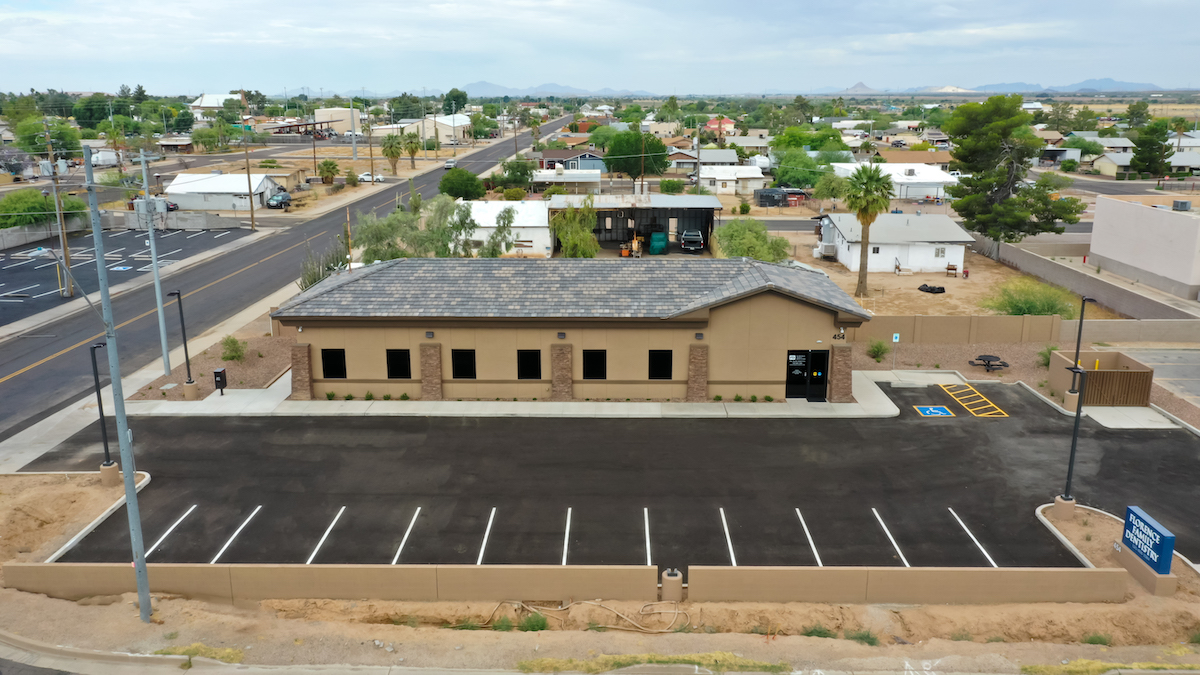 Exterior photo of brown dental office and parking lot
