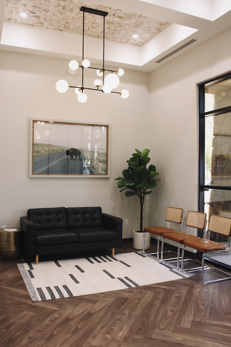 Black couch, tan chairs and artwork of a bison in a orthodontic office lobby