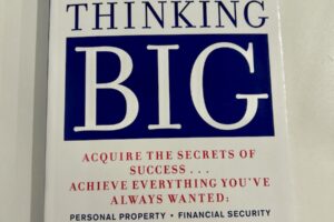 White book with blue text that reads "The Magic of Thinking Big"